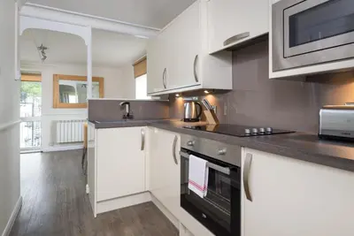 a kitchen with white cabinets and a stove top oven at Balmoral Apartment in Keswick