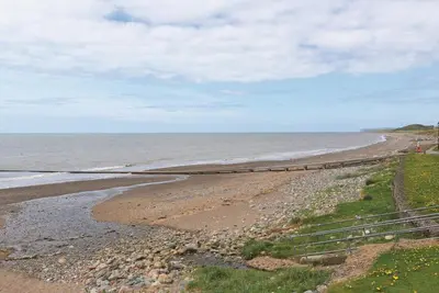 a beach with a fence next to the ocean at Bailey Ground Hotel in Seascale