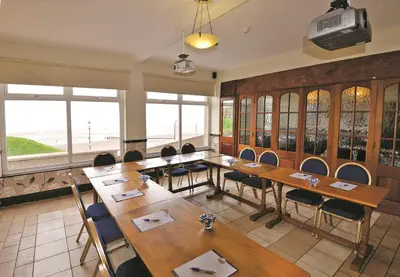 a conference room with wooden tables and chairs and windows at Bailey Ground Hotel in Seascale