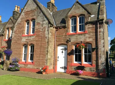 an old brick building with flowers on the door at St Matthews cottages in Allonby