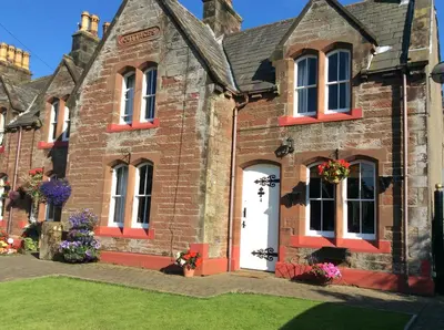 an old brick house with flowers on the door at St Matthews cottages in Allonby