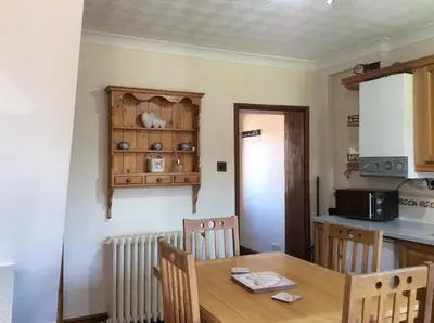 a dining room with a table and a kitchen at St Matthews cottages in Allonby