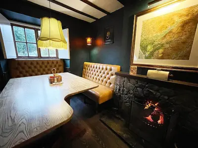 a dining room with a table and a fireplace at The Bridge Inn in Holmrook