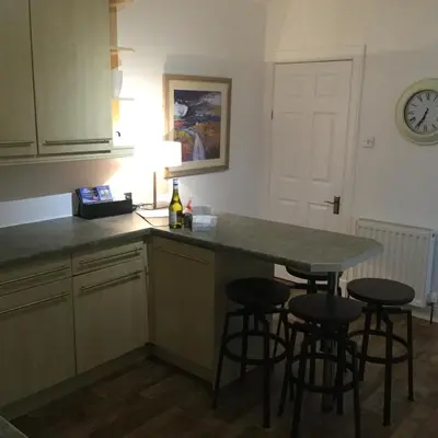 a kitchen with a counter with stools and a table at In House Garden Flat in Castle Douglas