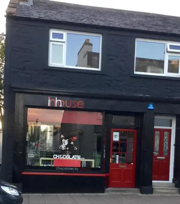 a black building with a store with a dog in the window at In House Garden Flat in Castle Douglas