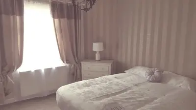 a bedroom with a bed and a lamp and a window at Dumfries Central apartment in Dumfries