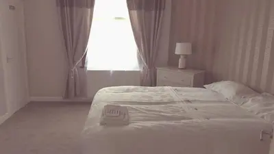 a white bed in a bedroom with a window at Dumfries Central apartment in Dumfries