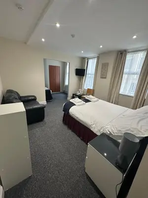 a hotel room with two beds and a chair at The Island & Fairfield in Douglas