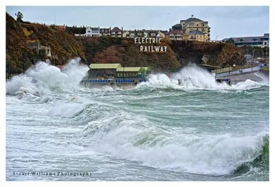 a group of waves in the ocean with buildings at The Island & Fairfield in Douglas