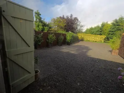 a green garage door in a garden with a driveway at The Little Fish in Cockermouth