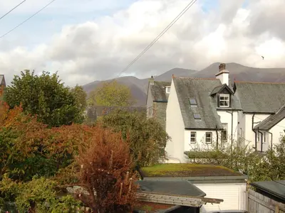 a white house with mountains in the background at Latrigg View in Keswick