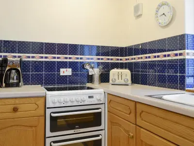 a blue tiled kitchen with a stove and a sink at Latrigg View in Keswick