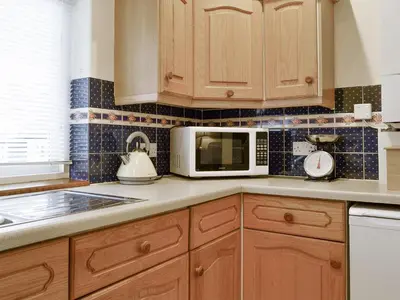 a kitchen with wooden cabinets and a microwave at Latrigg View in Keswick
