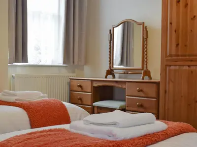 a bedroom with two beds and a dresser with a mirror at Latrigg View in Keswick