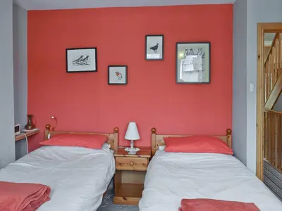 two beds in a room with a red wall at Saddleback in Keswick