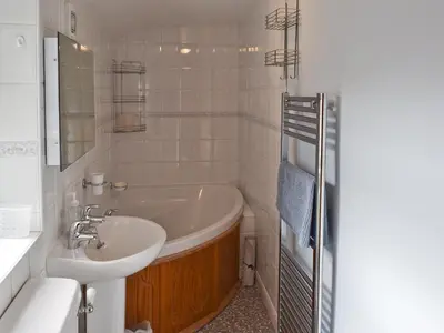 a white bathroom with a tub and a sink at Saddleback in Keswick
