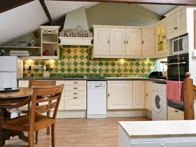 a kitchen with white cabinets and a table and chairs at Lund Cottage Was Gabriel's Cottage in Keswick