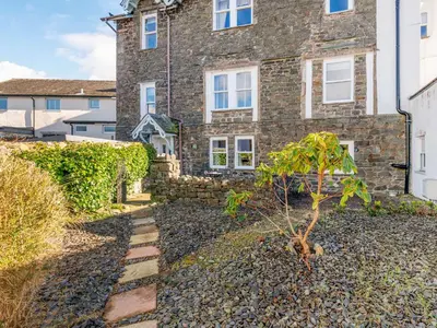 a stone house with a tree in front of it at Bunbury Cottage in Keswick