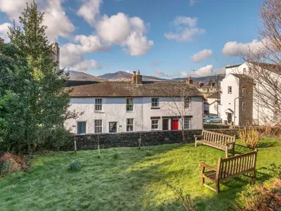 a white house with a bench in a yard at Bunbury Cottage in Keswick