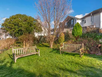 two wooden benches sitting in the grass in a yard at Bunbury Cottage in Keswick