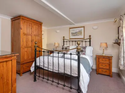a bedroom with a bed and a wooden cabinet at Bunbury Cottage in Keswick