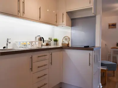a kitchen with white cabinets and a sink at Royal Views in Keswick