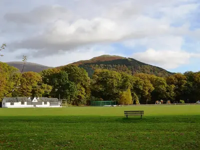 a bench in a field with a mountain in the background at 1 Greta Side Court in Keswick