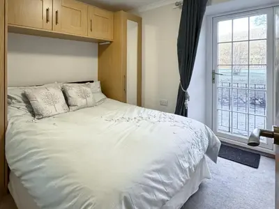 a bedroom with a large white bed and a window at 2 Greta Side Court in Keswick