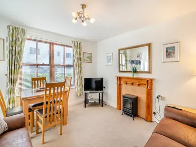 a living room with a table and a fireplace at Olivet - Hewetson Court in Keswick