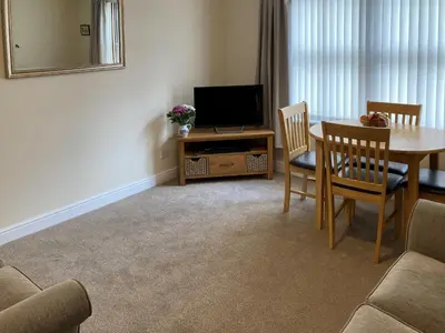 a living room with a table and a television at Ashbrooke- Hewetson Court in Keswick