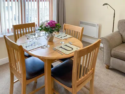 a wooden table with wine glasses and a vase of flowers at Ashbrooke- Hewetson Court in Keswick