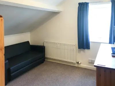 a living room with a black couch and a window at Wendover in Keswick