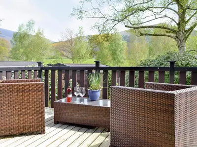 two wicker chairs and a table on a deck at Fell View Lodge in Keswick
