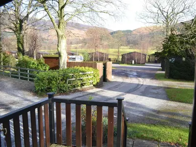 a wooden bench sitting next to a road with a fence at Ashness in Keswick