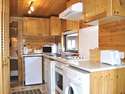 a kitchen with white appliances and wooden cabinets at Acorn Lodge - Burnside Park in Keswick
