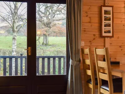 a door leading to a porch with a table and chairs at Whinny Brow - Burnside Park in Keswick