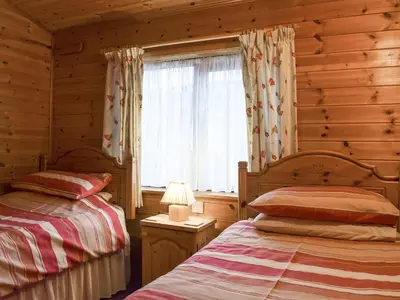 two beds in a log cabin bedroom with a window at Whiteside Lodge At Burnside Park in Keswick