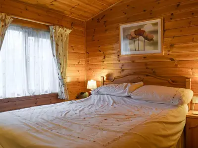 a bedroom with a bed in a log cabin at Whiteside Lodge At Burnside Park in Keswick