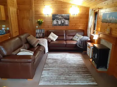 a living room with a brown leather couch and a fireplace at Ewe How - Burnside Park in Keswick