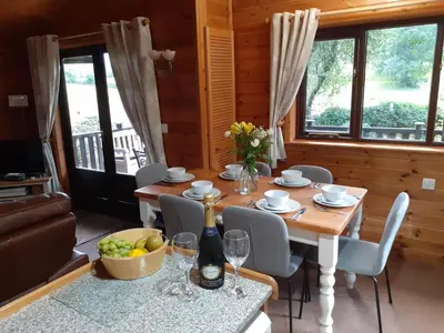 a dining room with a table and chairs and windows at Ewe How - Burnside Park in Keswick