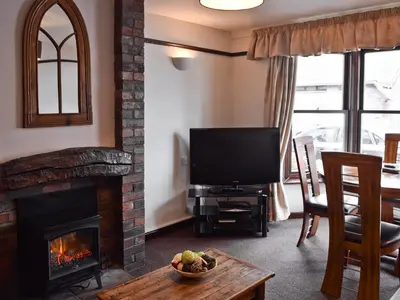 a living room with a fireplace and a television at Dairy Lodge in Keswick