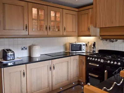a kitchen with wooden cabinets and a stove top oven at Dairy Lodge in Keswick