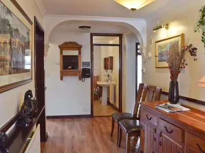 a living room with a table and chairs and a hallway at Dairy Lodge in Keswick