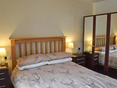 a bedroom with a bed and a large mirror at Dairy Lodge in Keswick