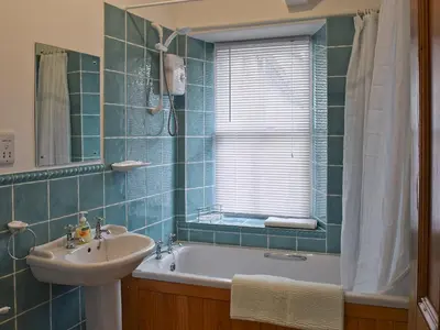 a bathroom with a tub and a sink and a window at Shorley Lodge in Keswick