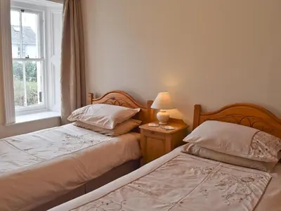 two beds in a bedroom with a lamp and a window at Shorley Lodge in Keswick