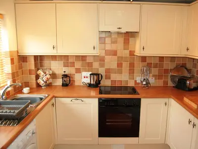 a kitchen with white cabinets and a black dishwasher at Brundholme Glen in Keswick