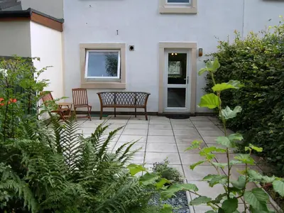 a patio with two chairs and a bench in front of a house at Brundholme Glen in Keswick