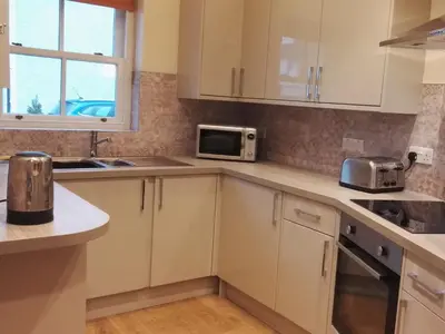 a kitchen with white cabinets and a microwave at Carthwaite in Keswick