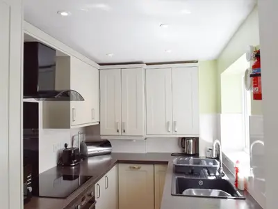a kitchen with white cabinets and a sink at Millie's Cottage in Keswick